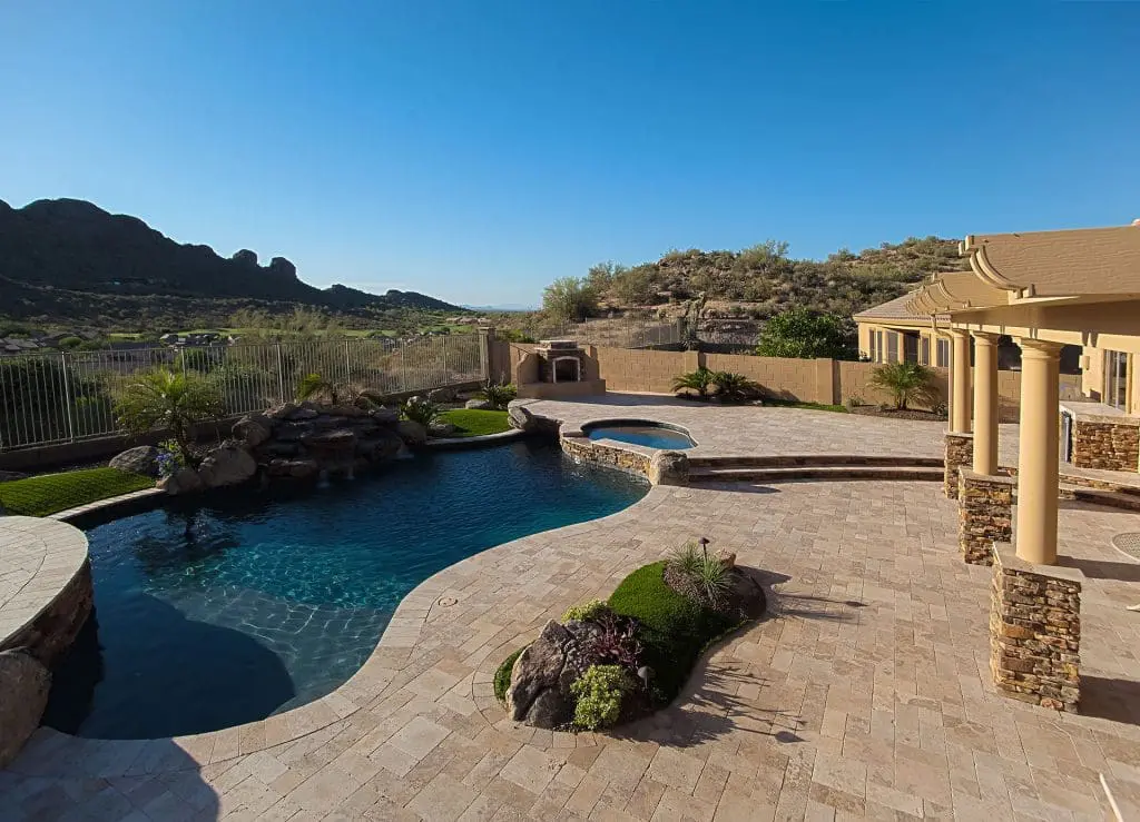 a pool and a house with large decking by Scottsdale pool builder